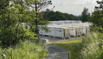 A photograph of a battery energy storage facility in a forested area in West Virginia, USA.