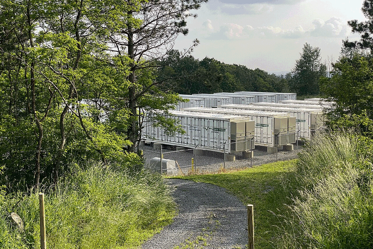A photograph of a battery energy storage facility in a forested area in West Virginia, USA.